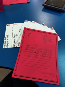 A letter written on red paper on a blue table with six addressed envelopes displayed under the letter.
