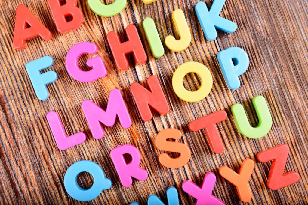 Colorful magnetic letter displayed on a wood background.