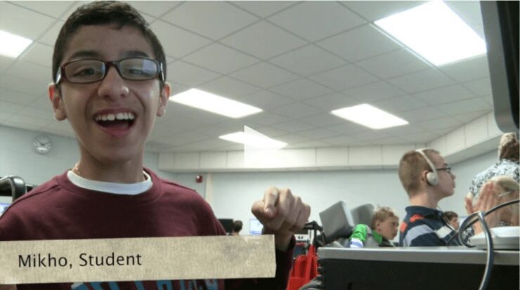 202205180955learningtoolsdonjohnstoncom Building Wings Building Wings A student named Mikho smiles at the camera in a classroom with other students working in the background