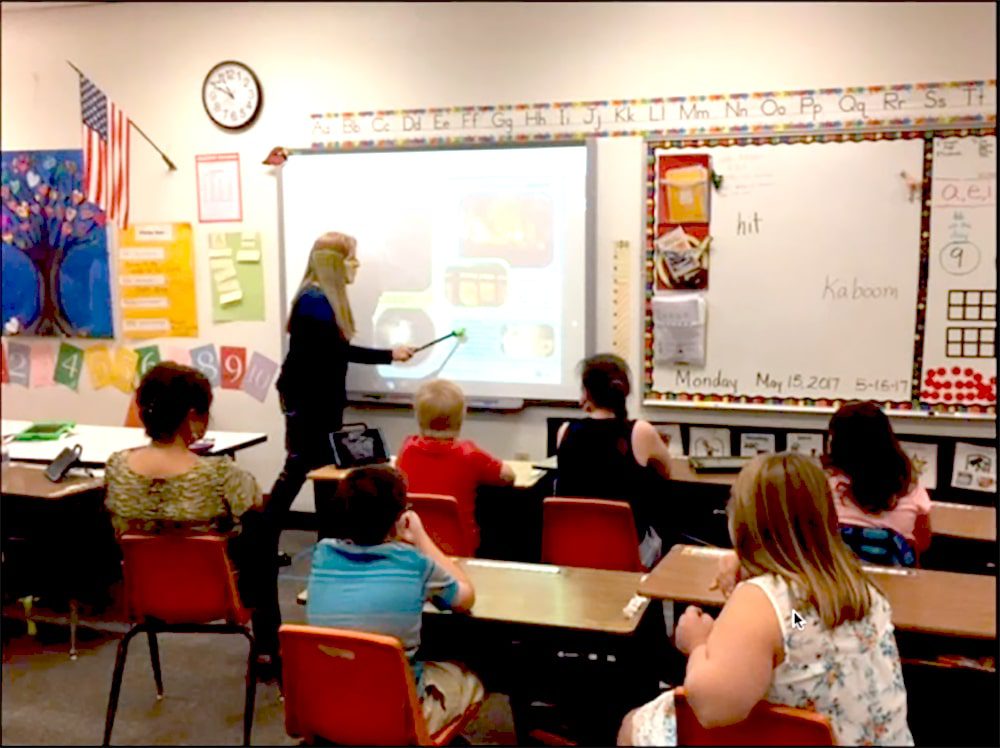 Caroline Musselwhite presents in front of a projector with a pointer, to students in a classroom.