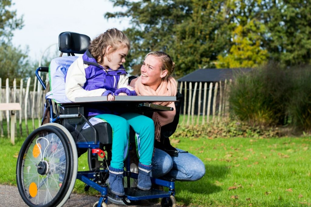 Depositphotos88312492xl20151 Building Wings Building Wings An adult smiles at a child in a wheelchair outdoors
