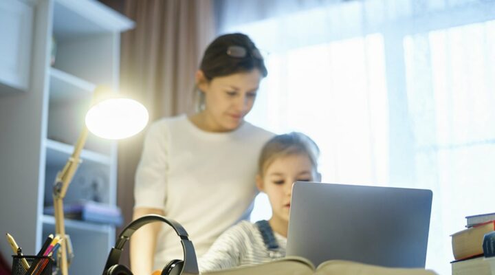 A mother and child look at a laptop together in their home