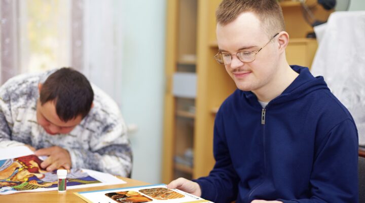 A student in a blue hoodie reads a Readtopia book in their home.