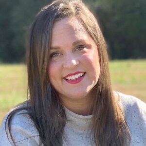Headshot of Allison Dennis wearing a grey sweater, outdoors.