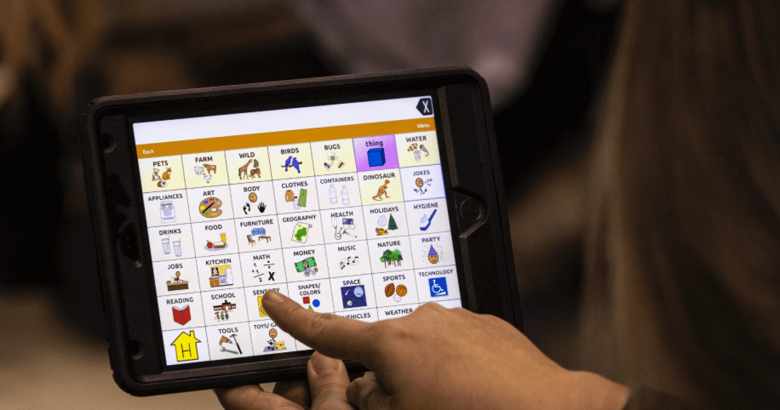 Someone points to a sensory icon on an AAC device.