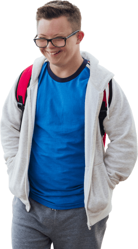 A student wearing a blue shirt, grey hoodie, and red backpack smiles.
