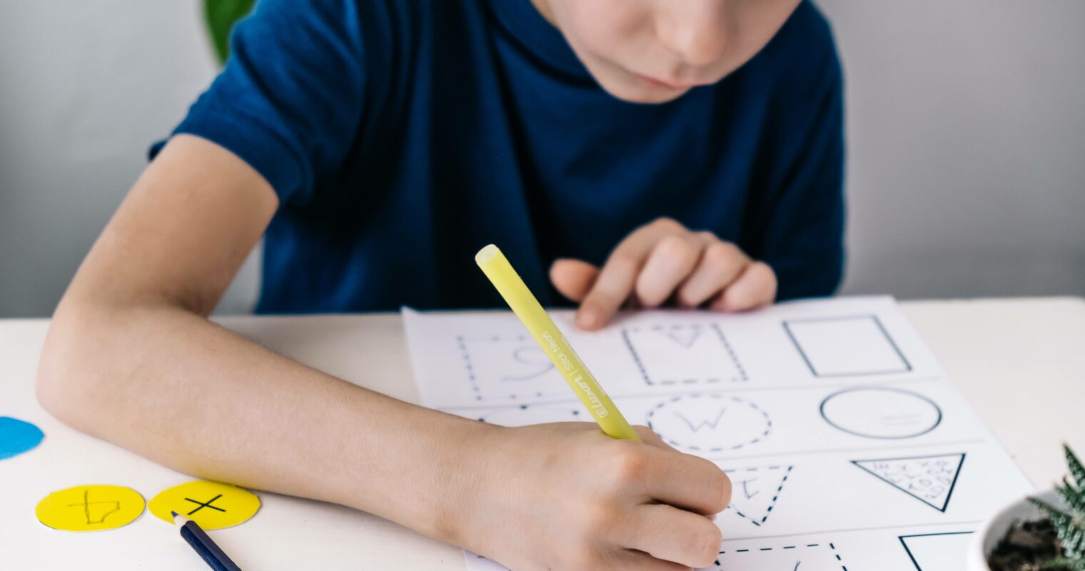 A student writing on a worksheet at a desk.