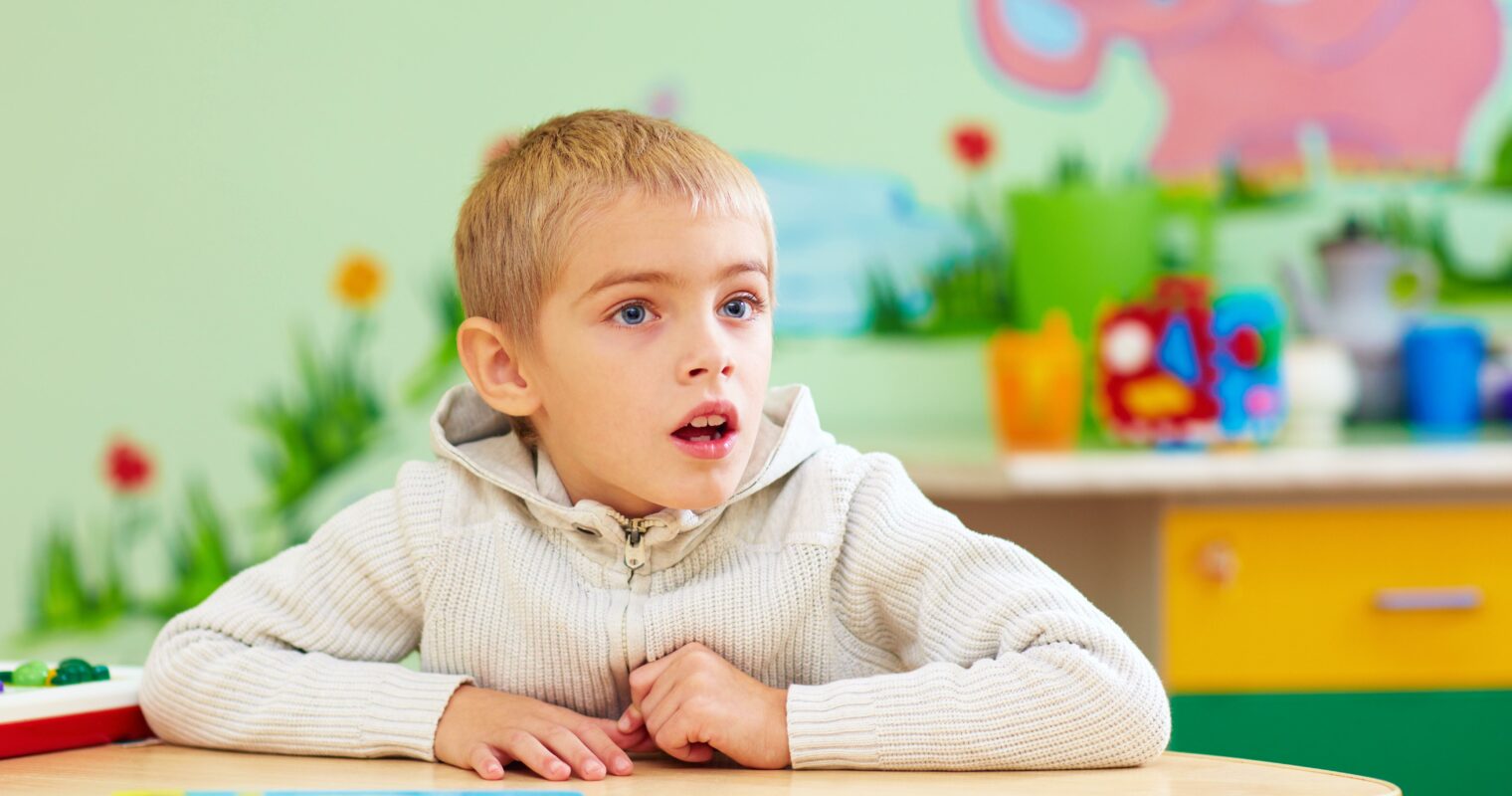 A student looking surprised while sitting at a desk, with a bright green background.
