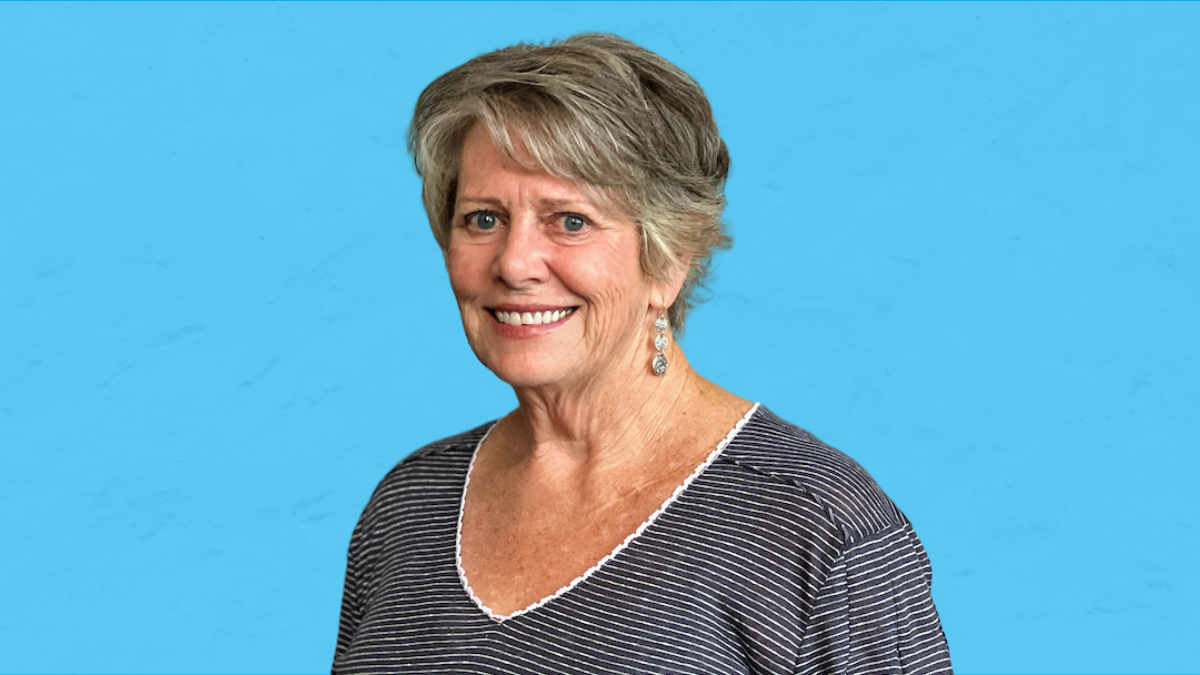 A woman, Mary Krenz, facing the camera with a blue background