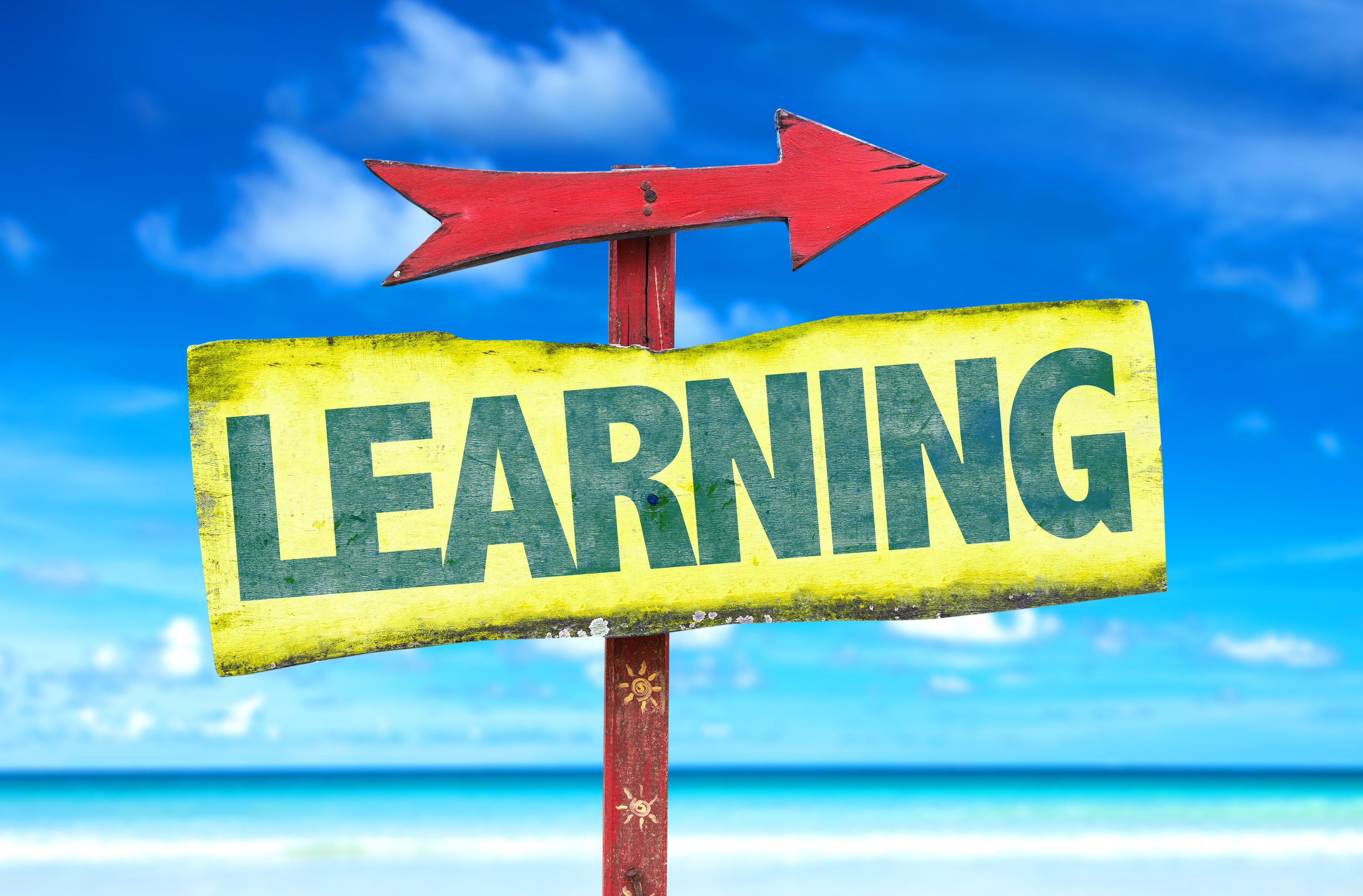 beach scene with a yellow sign with green text: Learning, with a red arrow pointing to the right.
