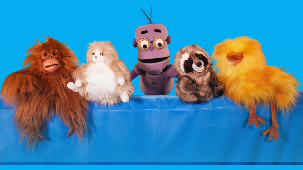 Blue background with five furry puppets including the purple robot Geartrude puppet from ReadtopiaGO