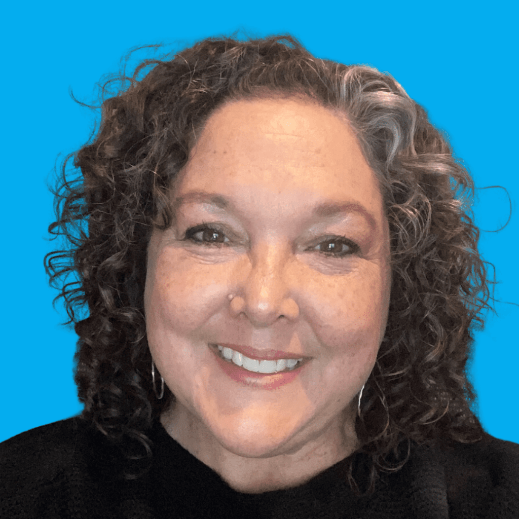 Headshot of woman with dark, curly hair, smiling.
