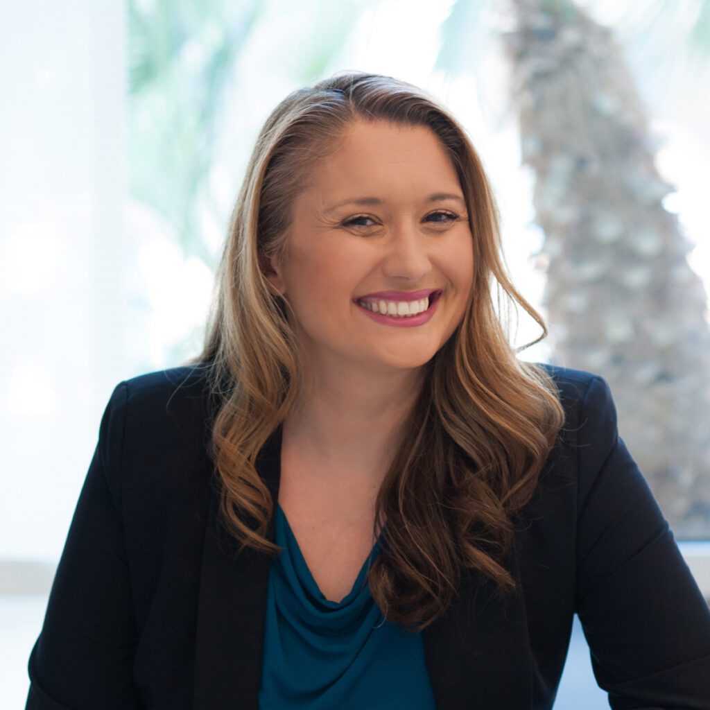 Woman smiling, white background, black blazer over blue shirt