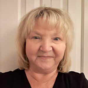 Woman smiling, tan background, blonde hair, dark eyes, fair complexion