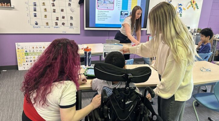 two teachers help to guide a young student with her specifically designed instruction