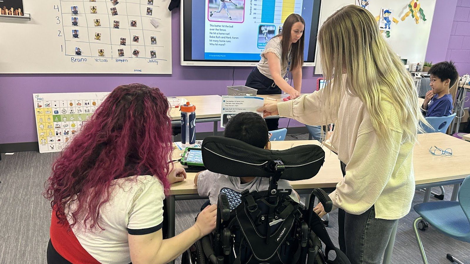 two teachers help to guide a young student with her specifically designed instruction