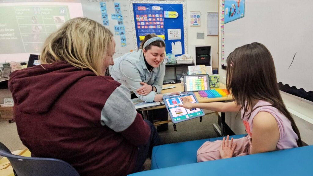 Two teachers guide a young student using systematic instruction.